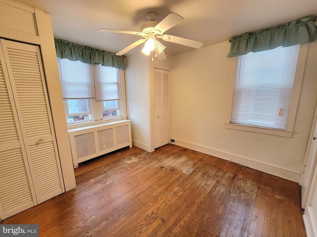 unfurnished bedroom featuring radiator, wood finished floors, baseboards, and ceiling fan