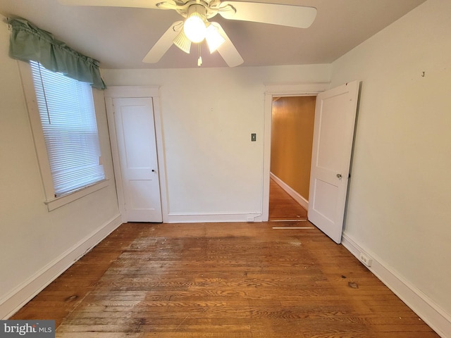 empty room featuring wood finished floors, a ceiling fan, and baseboards