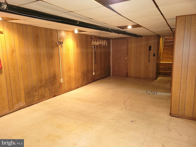 finished below grade area with tile patterned floors, wood walls, and stairs