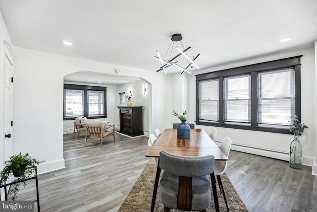 24 Cuthbert Rd, Cinnaminson, NJ 08077 - dining room with arched walkways, baseboard heating, light wood-style floors, a chandelier, and a glass covered fireplace