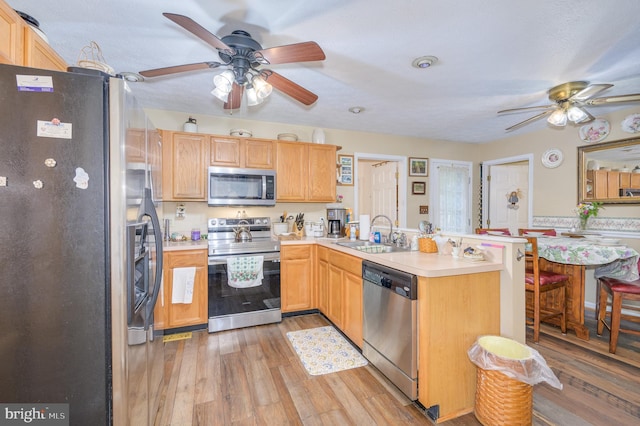 523 Zig Zag Ln, Inwood, WV 25428 - kitchen with appliances with stainless steel finishes, ceiling fan, a sink, a peninsula, and light wood-style floors