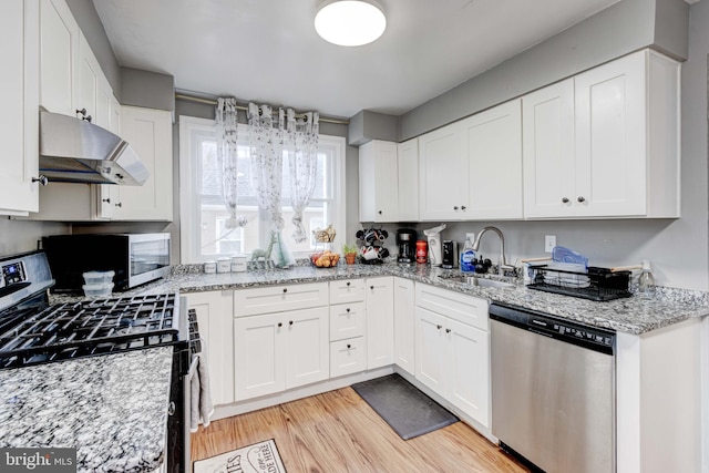 kitchen with appliances with stainless steel finishes, extractor fan, a sink, white cabinets, and light wood-style floors