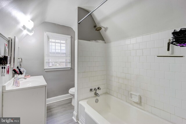 bathroom with lofted ceiling, toilet, vanity, wood finished floors, and bathing tub / shower combination