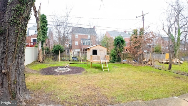 view of yard with a residential view, a fire pit, a playground, a storage shed, and an outdoor structure