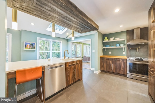 329 Dickinson Ave, Swarthmore, PA 19081 - kitchen featuring stainless steel appliances, wall chimney exhaust hood, a sink, a skylight, and light countertops