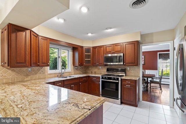 60 S Forge Manor Dr, Phoenixville, PA 19460 - kitchen featuring appliances with stainless steel finishes, a sink, light stone countertops, light tile patterned floors, and decorative backsplash