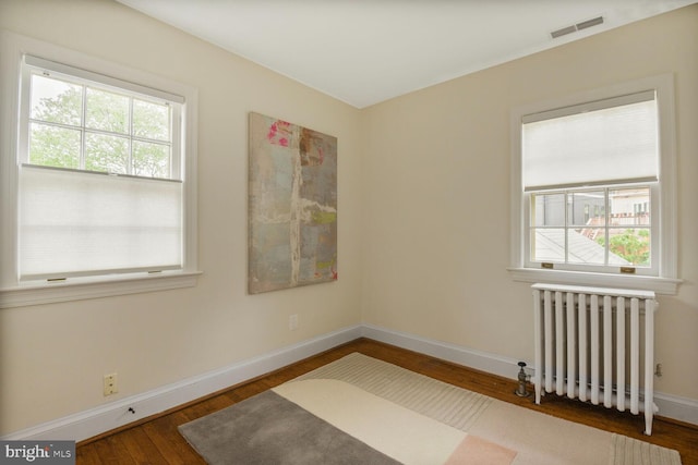 spare room featuring radiator heating unit, wood finished floors, and baseboards