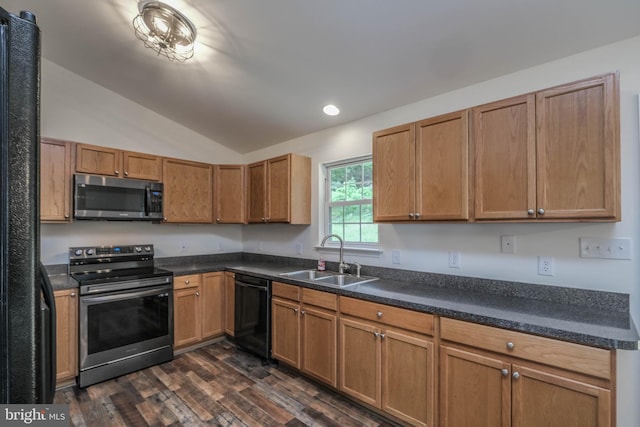 kitchen with stainless steel appliances, a sink, dark wood-style flooring, vaulted ceiling, and dark countertops