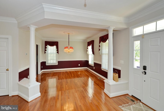 foyer featuring decorative columns, light wood-style floors, ornamental molding, and baseboards