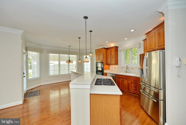 kitchen with stainless steel appliances, a center island, light wood-type flooring, a sink, and crown molding