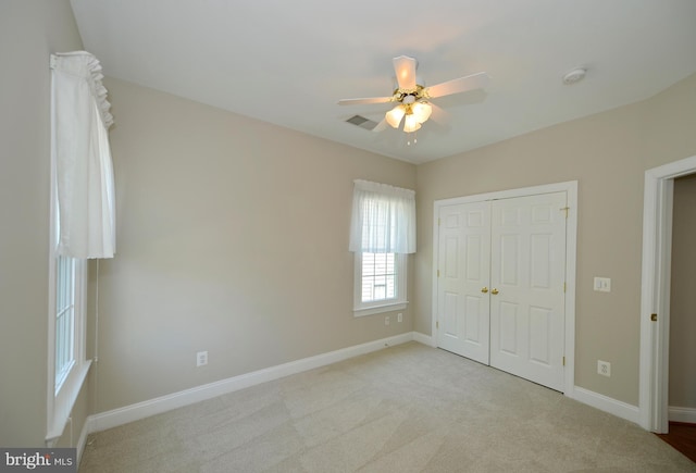 unfurnished bedroom featuring light colored carpet, baseboards, a closet, and a ceiling fan
