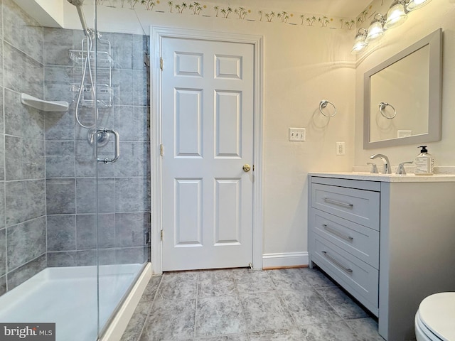 bathroom with a stall shower, baseboards, vanity, and toilet