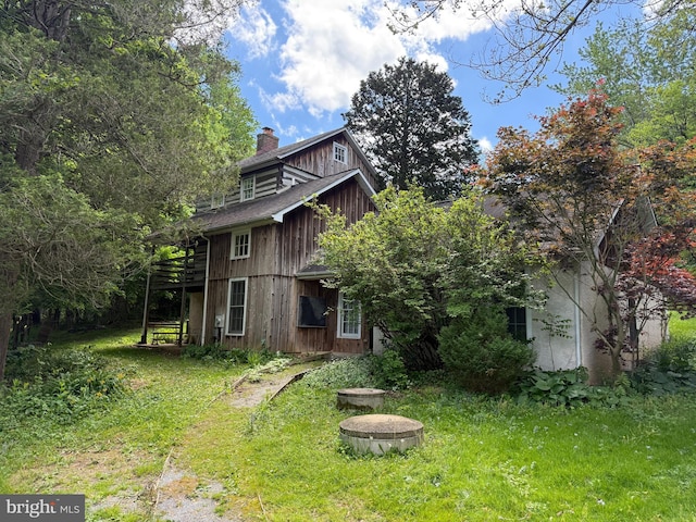 back of house featuring a chimney, a yard, and a wooden deck