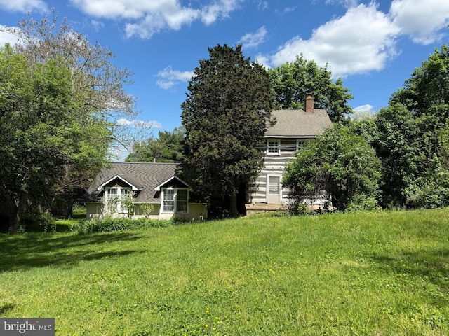 view of front facade featuring a chimney and a front yard