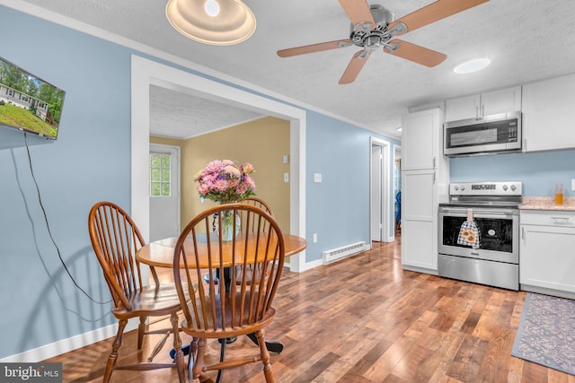 7570 Independence Cir, Charlotte Hall, MD 20622 - kitchen with stainless steel appliances, a textured ceiling, a baseboard heating unit, baseboards, and wood finished floors