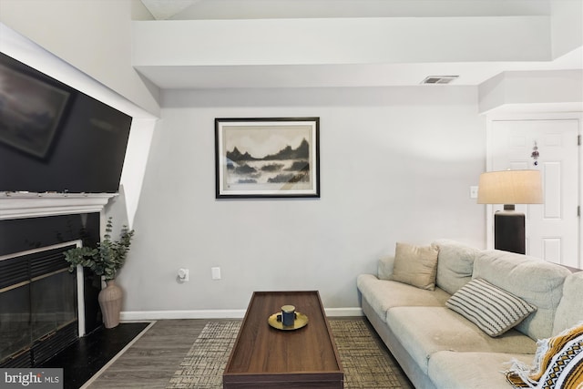 living area featuring dark wood-style floors, baseboards, and a glass covered fireplace
