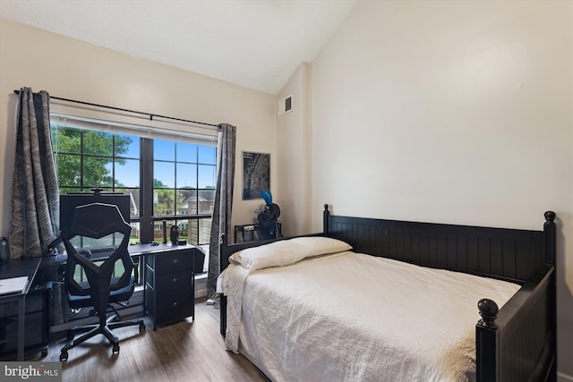 bedroom featuring vaulted ceiling, wood finished floors, and an office area