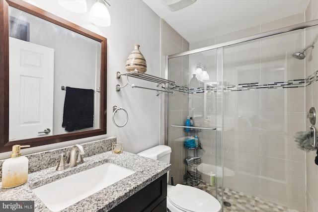 bathroom featuring a stall shower, toilet, and vanity