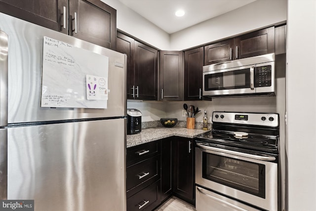 kitchen with stainless steel appliances, dark brown cabinetry, light stone counters, and recessed lighting