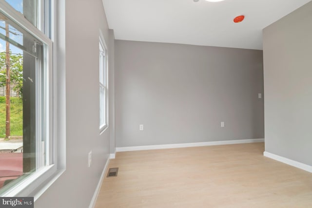 empty room with light wood finished floors, healthy amount of natural light, and baseboards