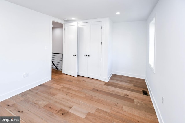 unfurnished bedroom featuring baseboards, wood finished floors, a closet, and recessed lighting