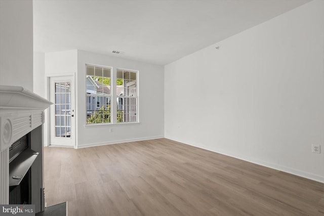 unfurnished living room featuring wood finished floors, a fireplace, and baseboards