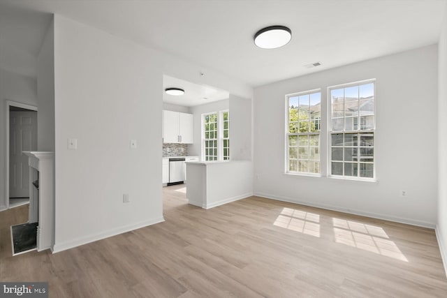 unfurnished living room with light wood finished floors, baseboards, and a fireplace
