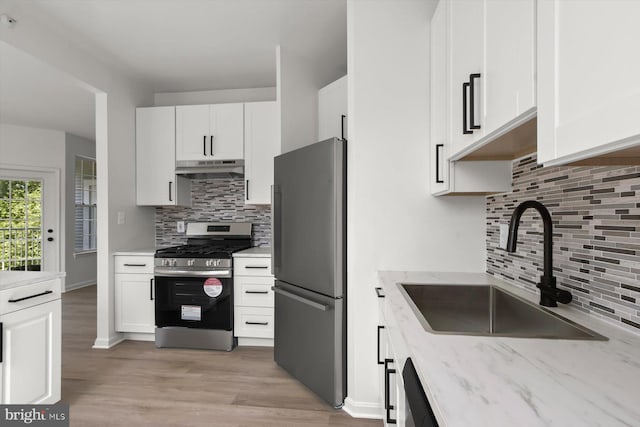 kitchen featuring stainless steel appliances, tasteful backsplash, a sink, and under cabinet range hood