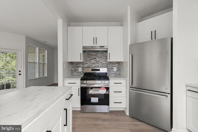 kitchen featuring stainless steel appliances, under cabinet range hood, backsplash, white cabinets, and light wood finished floors