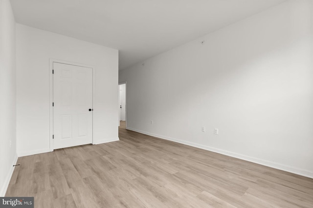 spare room featuring light wood-type flooring and baseboards