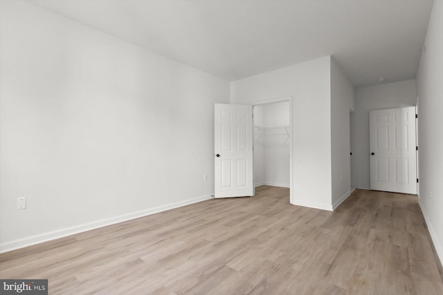 unfurnished bedroom with light wood-style flooring, baseboards, and a closet