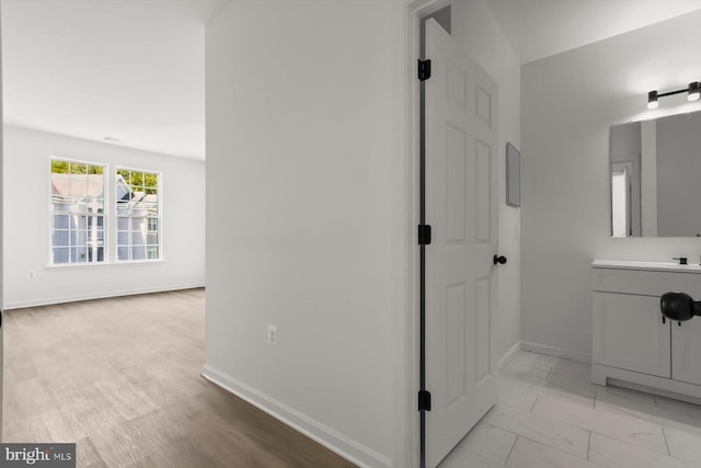 bathroom with baseboards, vanity, and marble finish flooring