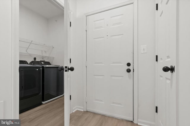 washroom with washing machine and clothes dryer, light wood-type flooring, and baseboards