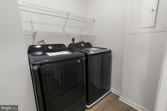 laundry area with washer and clothes dryer, wood finished floors, baseboards, and electric panel