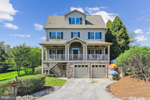 view of front of house featuring covered porch, stairs, asphalt driveway, an attached garage, and stone siding