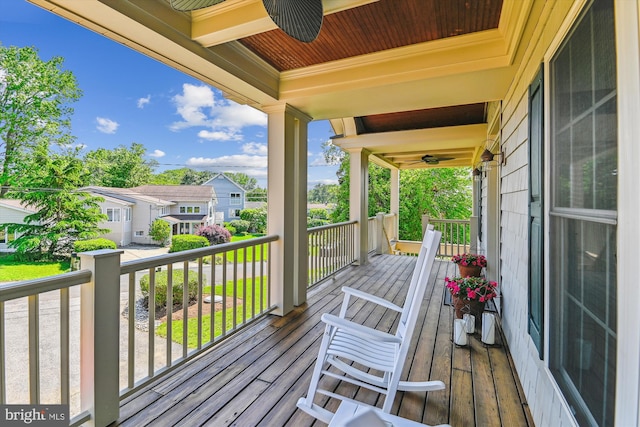 wooden terrace featuring a ceiling fan, covered porch, and a residential view