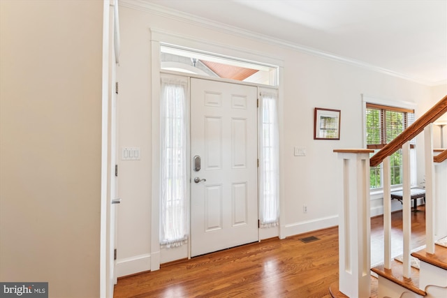 foyer entrance featuring stairway, ornamental molding, wood finished floors, and baseboards