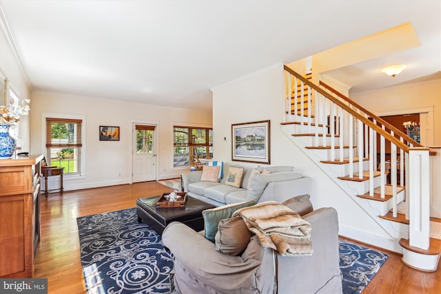 living area featuring stairway, wood finished floors, crown molding, and baseboards