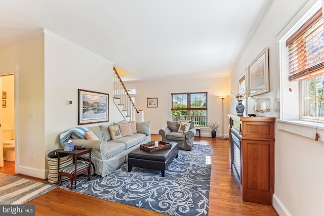 living area featuring wood finished floors, healthy amount of natural light, stairs, ornamental molding, and baseboards
