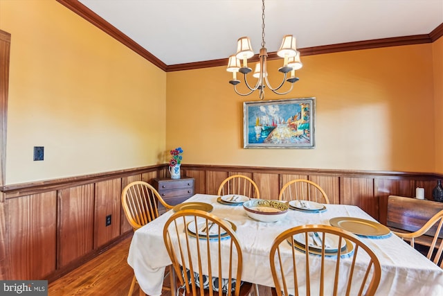 dining room featuring a wainscoted wall, a chandelier, ornamental molding, and wood finished floors