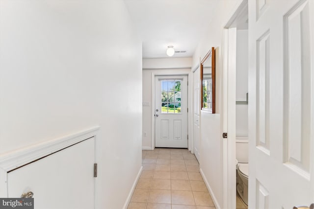 doorway to outside with light tile patterned flooring and baseboards
