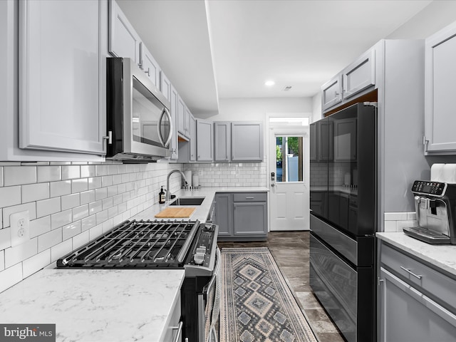 418 E Lanvale St, Baltimore, MD 21202 - kitchen with gas range, stainless steel microwave, a sink, refrigerator, and decorative backsplash