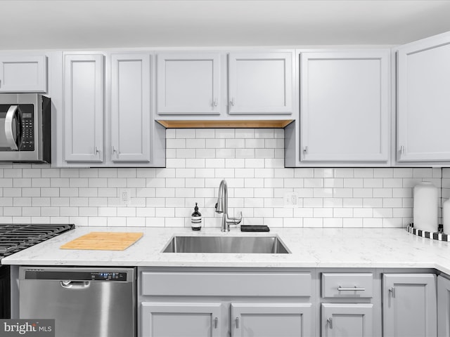 418 E Lanvale St, Baltimore, MD 21202 - kitchen featuring appliances with stainless steel finishes, a sink, decorative backsplash, and light stone countertops