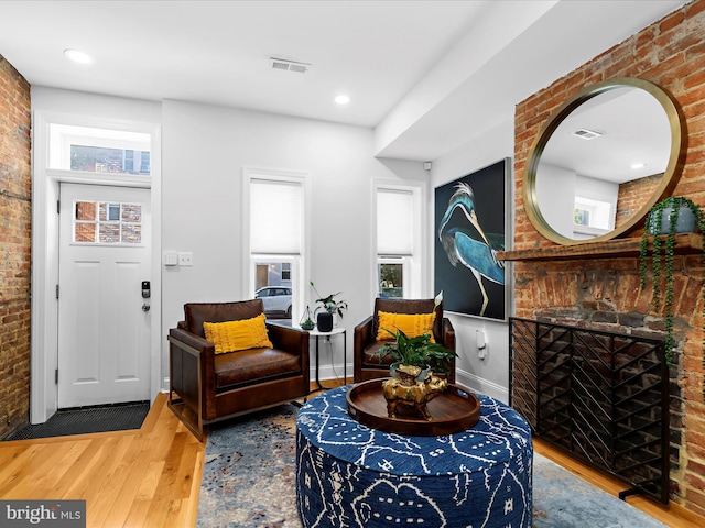 418 E Lanvale St, Baltimore, MD 21202 - living room featuring brick wall, wood finished floors, plenty of natural light, and a brick fireplace