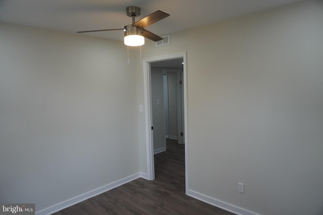 unfurnished room featuring a ceiling fan, baseboards, and dark wood finished floors