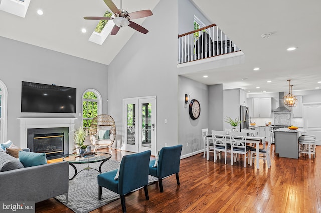 9609 Low Meadow Dr, Gaithersburg, MD 20882 - living room featuring a ceiling fan, a towering ceiling, dark wood finished floors, a skylight, and a glass covered fireplace