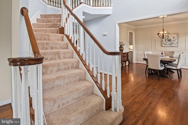 9609 Low Meadow Dr, Gaithersburg, MD 20882 - staircase featuring wood finished floors, crown molding, a chandelier, and a decorative wall