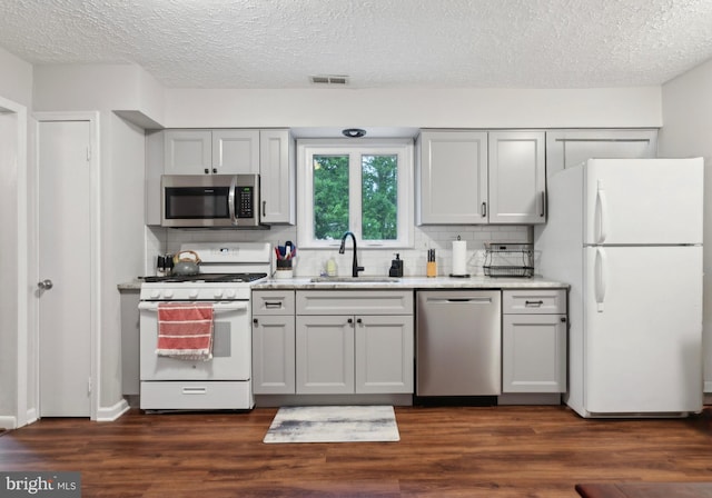 318 Spring Lake Blvd, Browns Mills, NJ 08015 - kitchen featuring stainless steel appliances, a sink, a textured ceiling, tasteful backsplash, and dark wood-type flooring