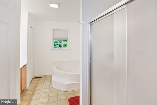 bathroom with a jetted tub, a stall shower, vanity, and baseboards
