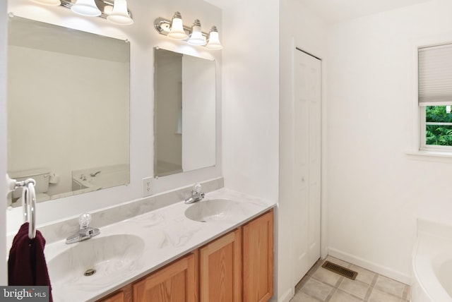 full bath featuring a tub to relax in, double vanity, and baseboards